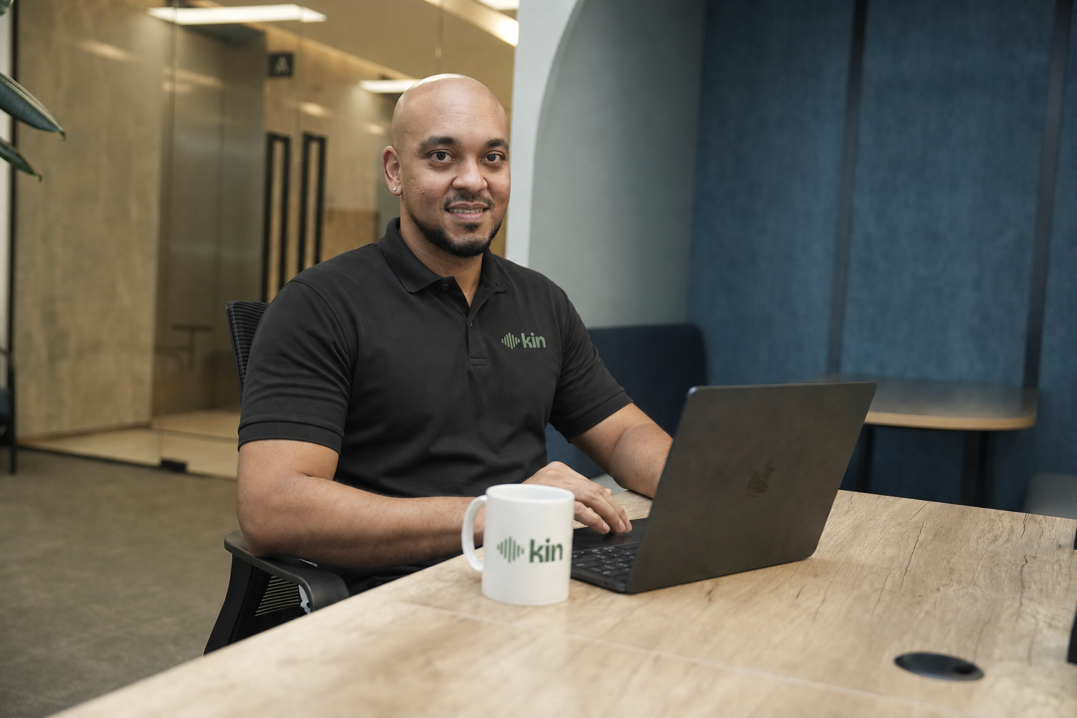 Antonio Xavier seated at a table with a laptop, wearing a black Kin polo